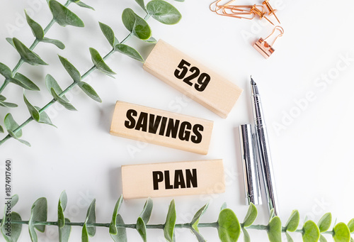529 savings plan phrase on wooden blocks with pens, clips and green leaves on white background