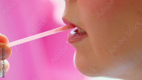 Macro closeup of a beautician applying lipstick with a wand to a female client in a beauty salon. Soft daylight and clean background, focus on lips and glossy texture, professional makeup service