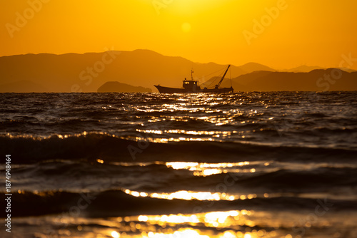 夕日の海を進む船