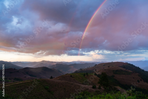 Scenic landscape of mountains in Thailand with a natural rainbow and purple clouds.