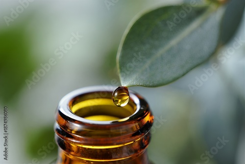 Golden essential oil dripping from leaf into amber bottle