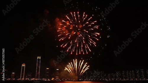 Spectacular fireworks display illuminating the night sky over a cityscape with towering buildings