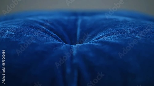 Close-up view of a plush, deep blue velvet cushion with a tufted center, showcasing its luxurious texture and rich color
