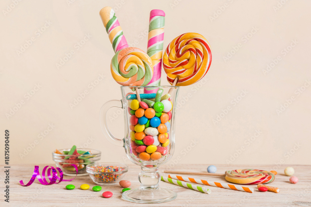 Fototapeta premium Colorful candies in cup on table on light background background. Large swirled lollipops. Creative concept of a jar full of delicious sweets from the candy store