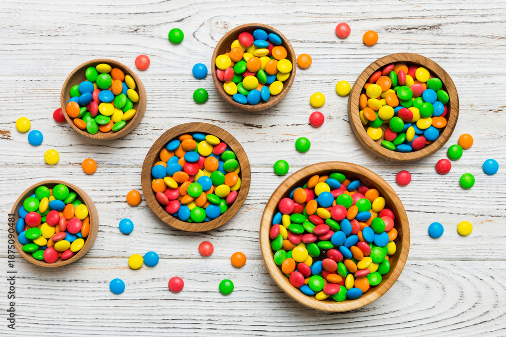 Fototapeta premium different colored round candy in bowl and jars. Top view of large variety sweets and candies with copy space