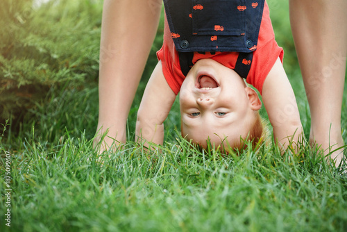 Mom and son are playing cheerfully together in the park in the summer. Mother is holding the baby boy. The child is laughing. Closeup portrait.