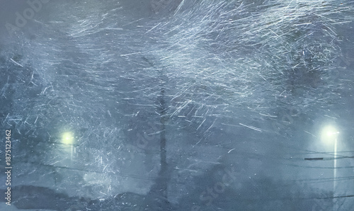 An abstract, cinematic view of a ferociously blowing blizzard at night, with swirling snow streaks caught in the bright glow of a street lamp against a dark, hazy winter background.