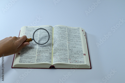 Konstfotografi Person holding magnifying glass over English dictionary