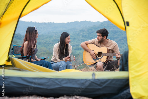 Canvas-taulu Group of three people sitting outside the yellow tent having fun conversation, f