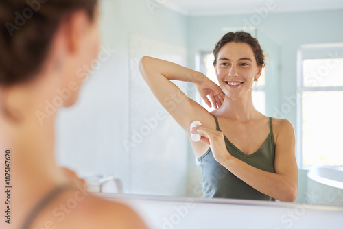 Beautiful mid adult woman applying deodorant roll-on