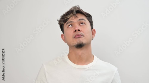 Video portrait of an Asian adult man looking up while thinking with tired expression. Mental fatigue, stress, pressure and emotional exhaustion concept in everyday lifestyle.