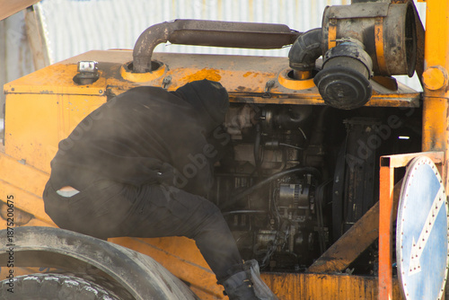 Mechanic Repairing Engine of Heavy Construction Machinery Outdoors
