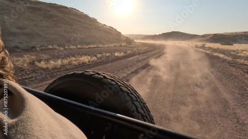 A view from a moving car. Dust on the road, a person's hair fluttering in the wind.