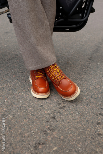 Stylish brown leather work boots with yellow laces on asphalt