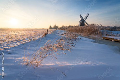 A cold winter sunrise at a windmill in the Dutch countryside.