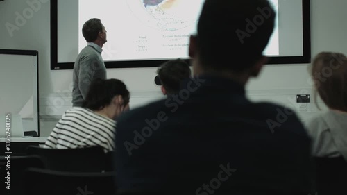 Rear view of a classroom with a man presenting on a projector screen