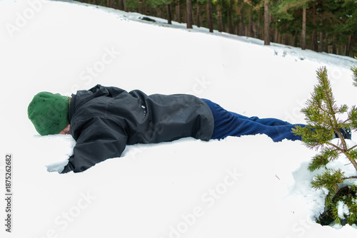 Man lying face down in snow after playful winter fall
