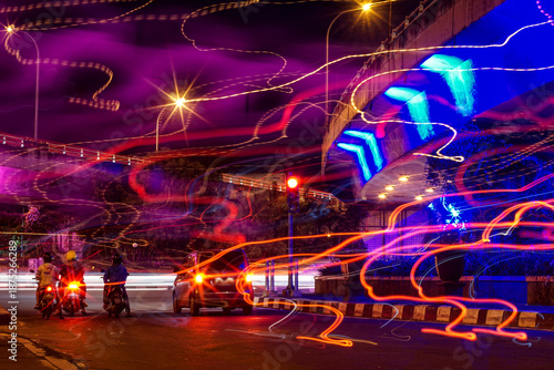 Long exposure abstract city scene with colorful light trails, traffic motion and urban infrastructure at night. Dynamic futuristic background representing speed, energy, technology and nightlife