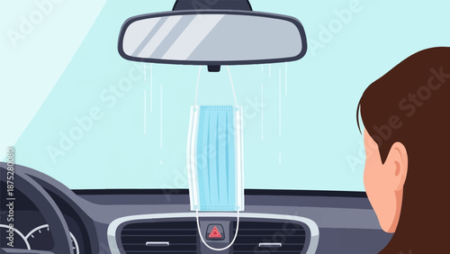 Inside a car, a blue protective face mask hangs from the rearview mirror