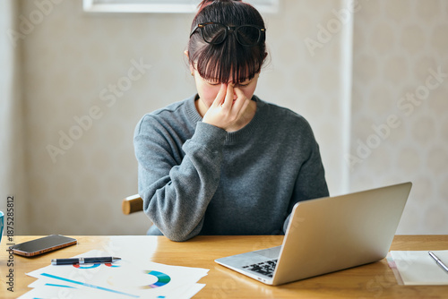 Stressed Businesswoman Rubbing Eyes While Working on Laptop at Desk
