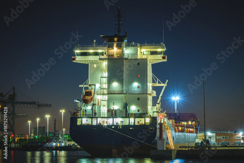 Large Industrial Cargo Ship Illuminated at Night in Commercial Port