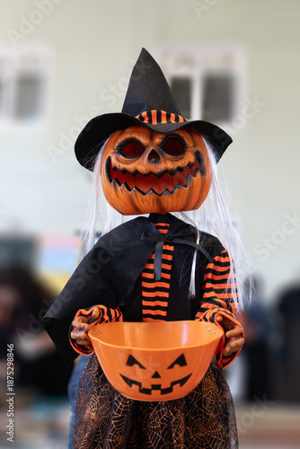 Spooky Halloween witch figure with a pumpkin head holding a candy bucket for trick-or-treating