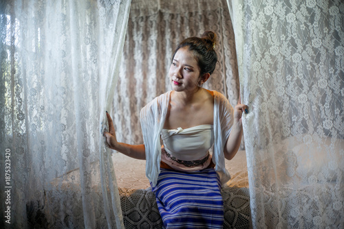 Beautiful young Asian woman in traditional Thai Lanna dress in an old house in Chiang Mai, Thailand.
