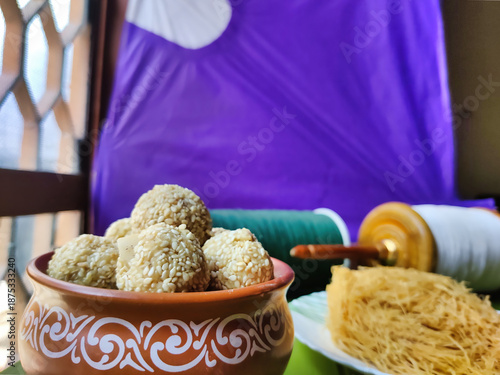 Picture of traditional Indian festival of Makar Sankranti delights. Focus on Sesame Ladoos with kites and pheni sweet in defocused background shot during daylight
