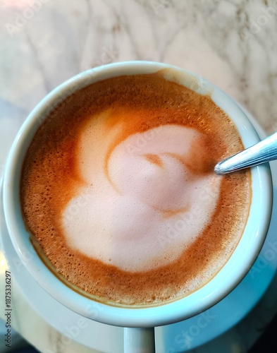 Cup of coffee with milk and rich foam on restaurant table drink background