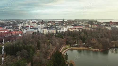Helsinki city skyline and Hietaniemi park by Lapinlahti bay under overcast autumn sky, Finland capital urban landscape with residential buildings and sea coast aerial view scene.
