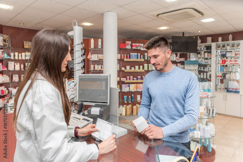 Obraz premium Female Pharmacist selling medications to a male patient holding a prescription in a pharmacy