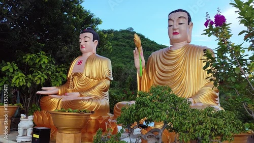 Two serene sitting Buddha statuesat Chua Da Bao Pagoda in Nha Trang, Vietnam. Peaceful spiritual scene in a traditional temple surrounded by nature and mountain views.