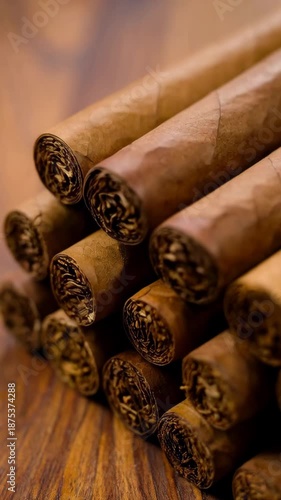 Arrangement of unlit brown cigars on polished wood surface in close up, showcasing tobacco leaves and textured wraps, for relaxation