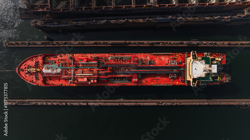 Red LPG tanker escorted by tugboats on calm sea waters, maritime transport, industrial shipping, logistics, and port operations concept.