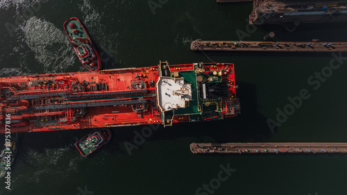 Red LPG tanker escorted by tugboats on calm sea waters, maritime transport, industrial shipping, logistics, and port operations concept.