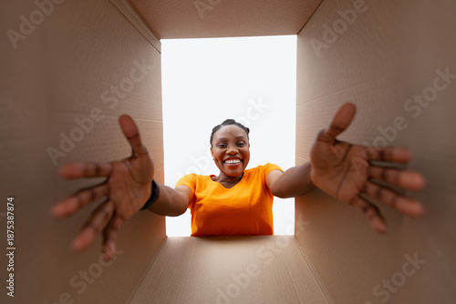 Obraz na płótnie Happy black woman unpacking cardboard parcel, receiving online delivery, bottom view