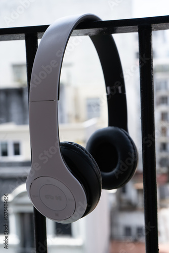 White wireless headphones hanging on a railing, isolated