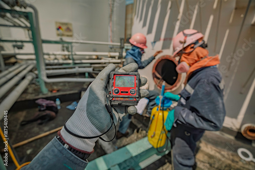 Worker hand holding gas detector inspection safety gas testing at front manhole