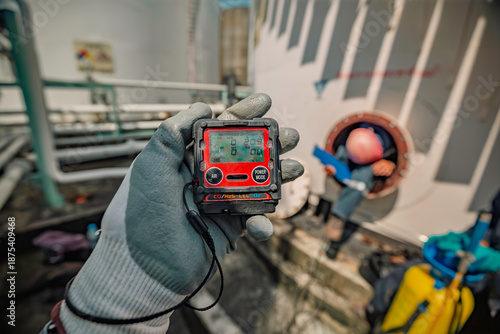 Worker hand holding gas detector inspection safety gas testing at front manhole