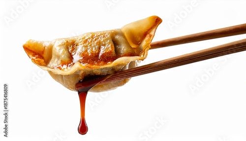 Wallpaper Mural chopsticks holding a pan fried gyoza dumpling with dripping sauce isolated with white background Torontodigital.ca