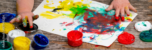 Child creating abstract artwork with finger painting, enjoying sensory play and creative exploration of colorful paints.