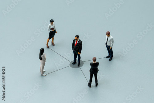 Fotografija Miniature business people connected by lines to a central leader
