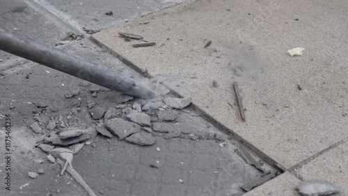 Removing a concrete floor with a hand hammer. Concrete rubble on the construction site of a house. Destruction of old tiles. Male construction removes the old tile from the floor with a hammer drill.