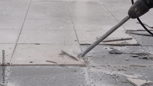 Removing a concrete floor with a hand hammer. Concrete rubble on the construction site of a house. Destruction of old tiles. Male construction removes the old tile from the floor with a hammer drill.