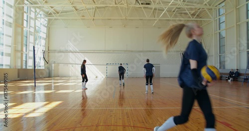 The girls lose the balls during practice and quickly pick them up.. Female volleyball players meet before training, then practice receiving and passing the ball in pairs.