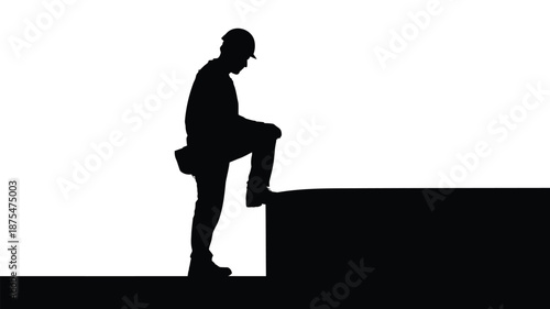 Silhouette of construction worker on ledge in hard hat and tool belt