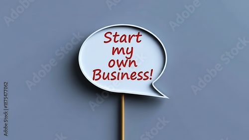 Speech bubble sign on a stick with red text saying 'Start my own Business!' against a plain gray background, representing entrepreneurial aspirations and new ventures.