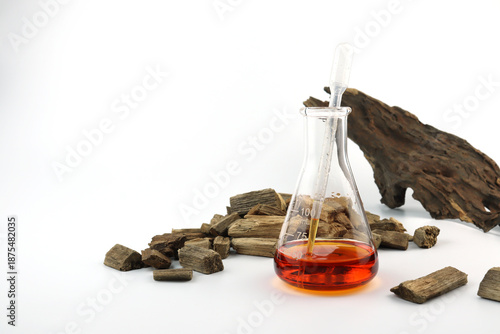 chemical beaker or flask is used on white table with blotting paper fragrance bottle and agarwood oud oil bottle are used to blend nice scent for making perfume and reed diffuser by perfumer lab test