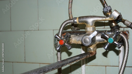 Old rusty faucet in bathroom with limescale and corrosion on tiles background
