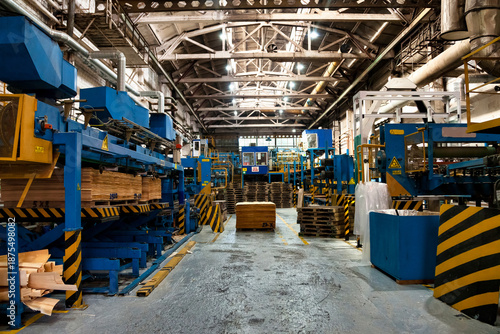 Interior of manufacture plant with stock wood treatment on automatic machinery, woodwork. Wood treatment process of plywood in industrial factory. Woodwork plywood industry concept. Copy ad text space